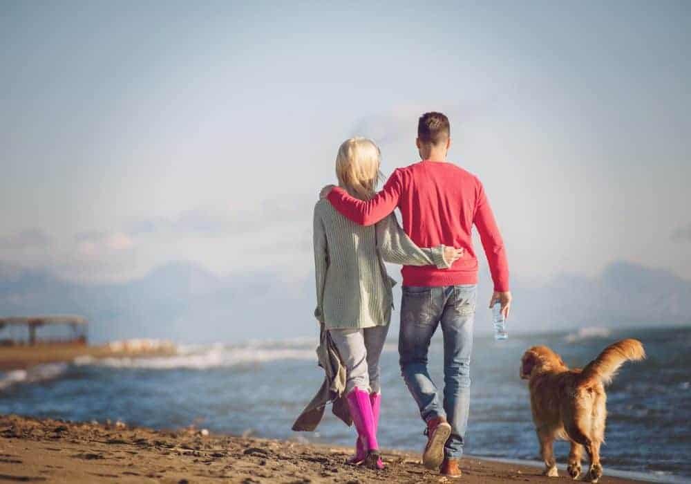 ouple with dog having fun on beach on autmun day