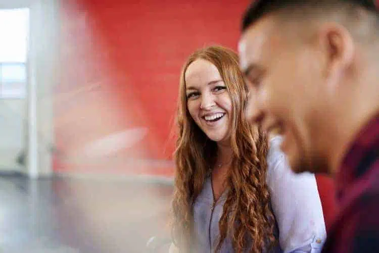 young woman smiling at young man in office meeting