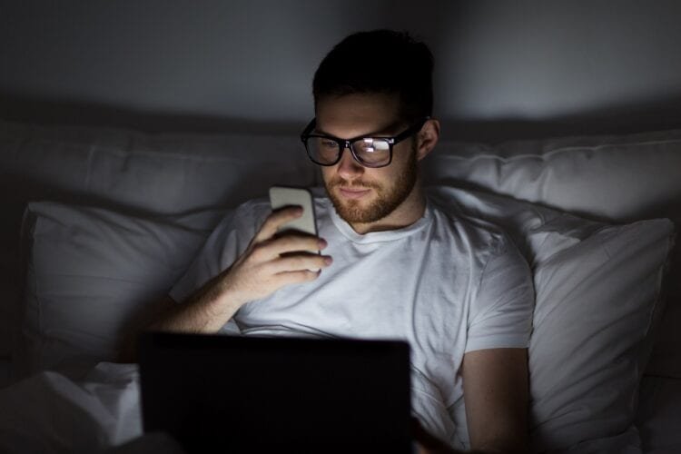 Sharing a Bedtime: Why it's Essential to Your Relationship 5 man with laptop and smartphone at night in bed PLVQ98V rekindle the flame
