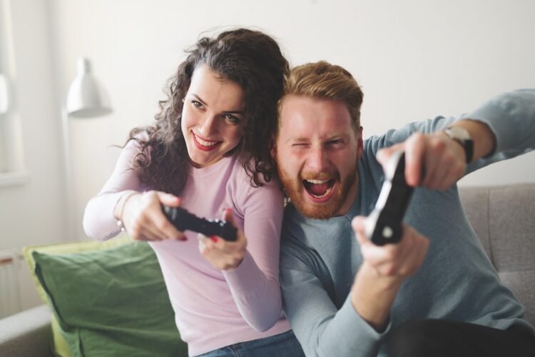 Happy couple playing video games on console and having fun