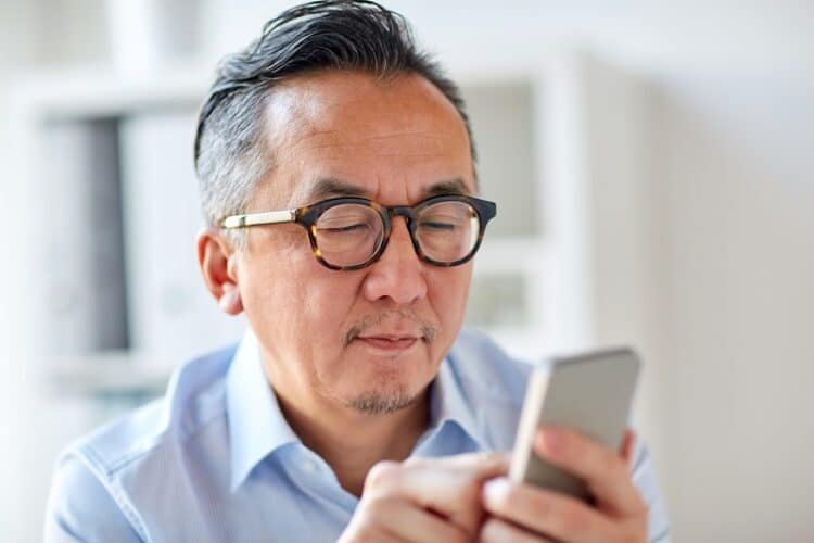 business, people, communication and technology concept - close up of businessman texting on smartphone at office