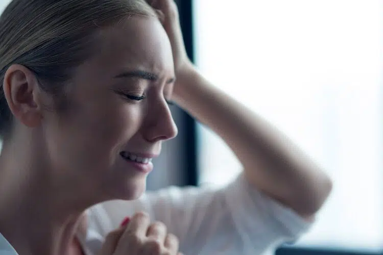 6 Insidious Dangers of Dealing With Emotional Manipulation In a Relationship 5 Young woman standing leaning on window crying depressed face close-up