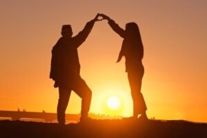 happy, healthy, and intimate couple holding hands in front of a sunset