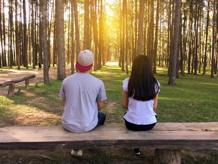 Man and woman sitting on bench in woods, dating red flags