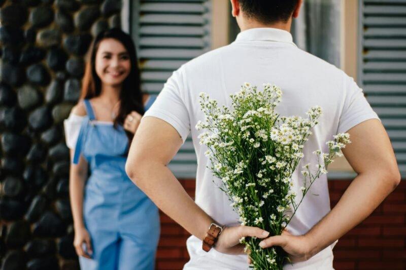 Man holding baby s breath flower in front of woman standing near marble wall