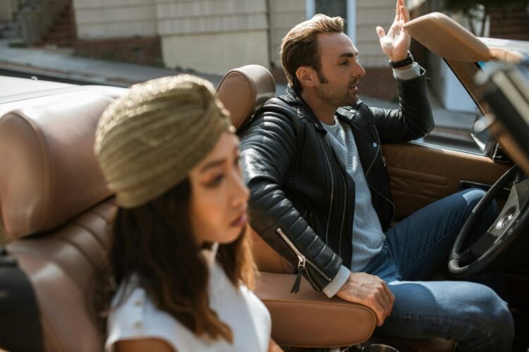 Man in black leather jacket sitting beside woman having an argument