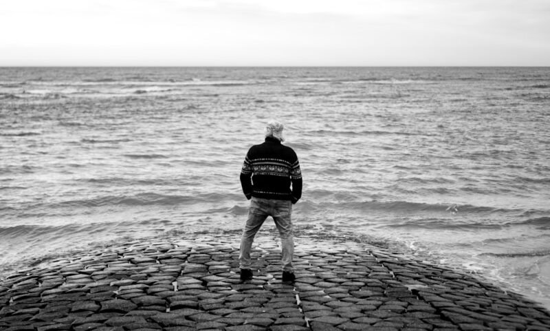 a man standing on top of a stone pier next to the ocean